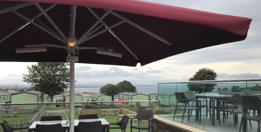 Large red umbrella at caravan park by the sea. Food service industry parasols